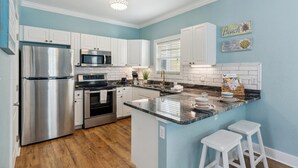 A modern kitchen with white cabinets, stainless steel appliances, a marble countertop, and a blue accent wall. - Family-Friendly Pensacola Home < 1 Mi to Beach! (Pensacola)