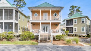 A two-story house with a front porch, a staircase leading to the entrance, and a small garden area. - Family-Friendly Pensacola Home < 1 Mi to Beach! (Pensacola)