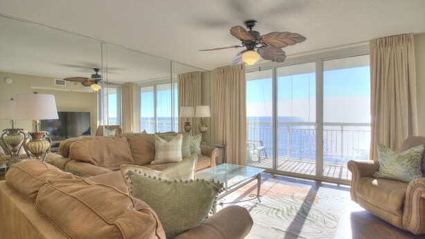 A spacious living room with a large sofa set, a glass coffee table, and a ceiling fan. - Views for days! Oceanfront 3 Bedroom 3 Bath Crescent Shores North Myrtle Beach (North Myrtle Beach)