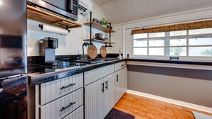 Una cucina moderna con forno a microonde integrato, macchina da caffè e mensole in legno.