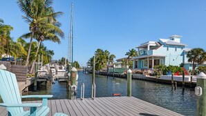 A wooden dock with chairs, a boat, and a house with a dock.