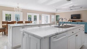 A spacious kitchen with a large island, white cabinetry, and a built-in dishwasher.