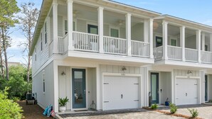 Un immeuble résidentiel à deux étages, doté d’un porche avant couvert, de deux garages et d’un jardin paysager à l’avant.