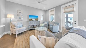 Un salon avec un canapé, des fauteuils, une table basse et un téléviseur.