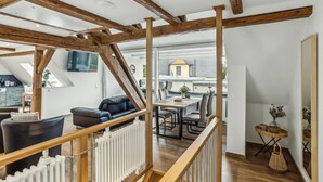 Um amplo loft com vigas de madeira aparentes, uma área de estar aconchegante e vista para a cidade.