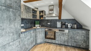 Uma cozinha moderna com armários cinza, forno embutido e cafeteira.