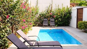 En pool med två solstolar och ett trädäck.