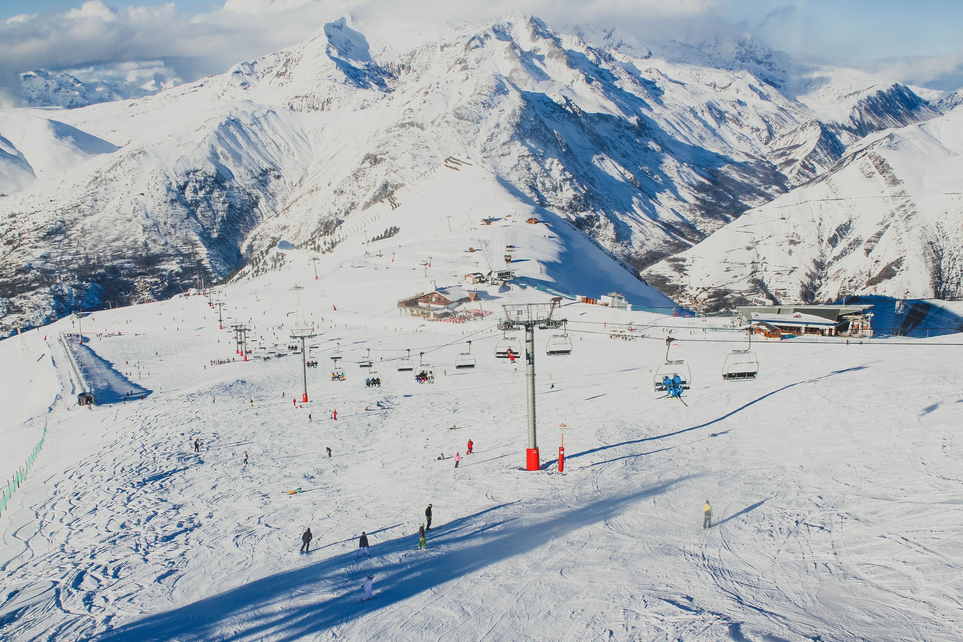 A snow-covered ski slope with ski lifts and a mountain backdrop.