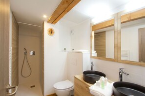 A modern bathroom with a shower, toilet, and two sinks.