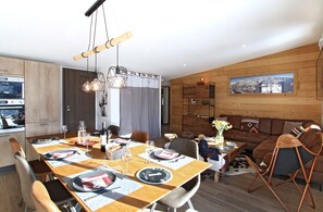 Enjoy meals in this stylish dining area with a wooden table, pendant lights, and a comfortable seating area.