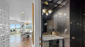 Un bagno moderno con lavabo in marmo, pareti piastrellate scure e pavimento decorato.