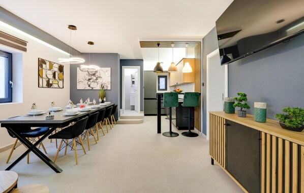 A modern kitchen with a built-in oven, a dining area with a long table and chairs, and a TV mounted on the wall. - Luxurious home in Stubicke Toplice with sauna (Stubicke Toplice)