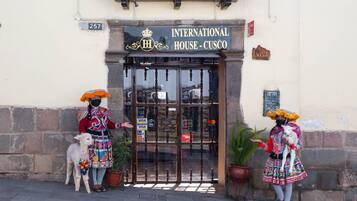 The entrance to the International House - Cusco, featuring a traditional gate, a potted plant, and a sign indicating Visa acceptance.