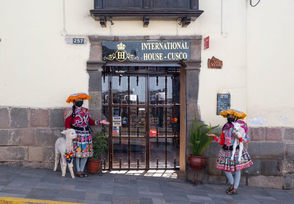 The entrance to the International House - Cusco, featuring a traditional gate, a potted plant, and a sign indicating Visa acceptance. - Hostal International House Cusco (Cusco)