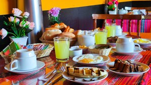 A breakfast table with various dishes, including eggs, pastries, and a coffee pot. - Hostal International House Cusco (Cusco)