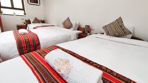 A hotel room with two beds, each with patterned bedspreads and pillows, a nightstand with a lamp, and a window with a view. - Hostal International House Cusco (Cusco)