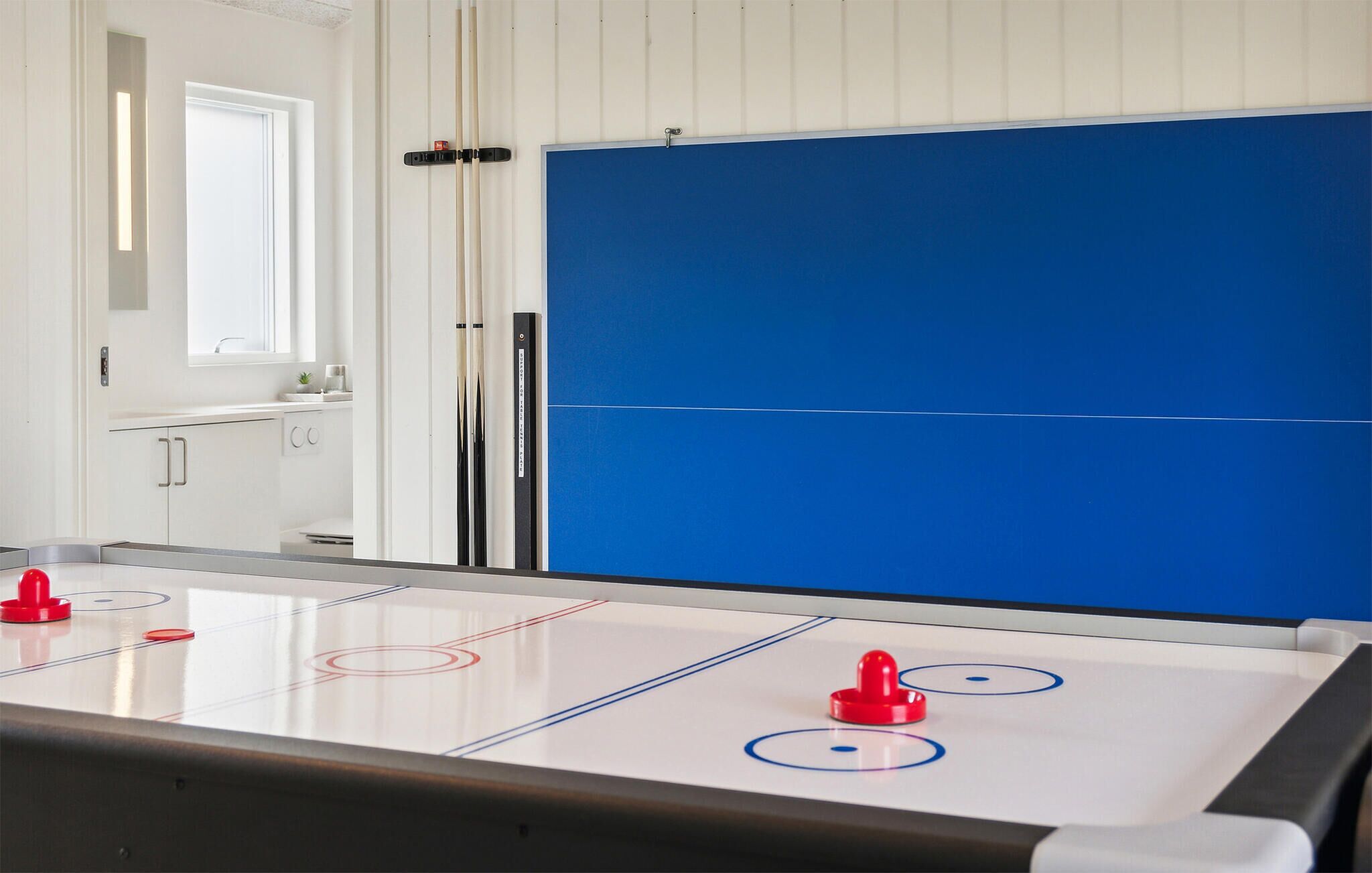 Une pièce avec une table de jeu de palet, un mur bleu et une porte blanche.