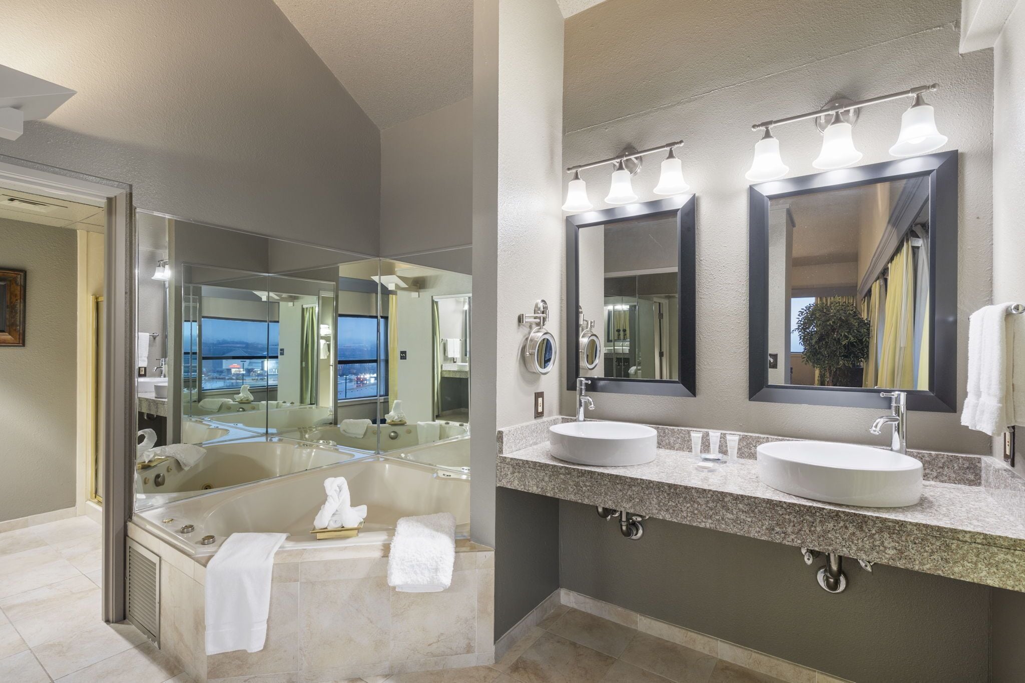 A modern bathroom with a large bathtub, two sinks, and a large mirror.