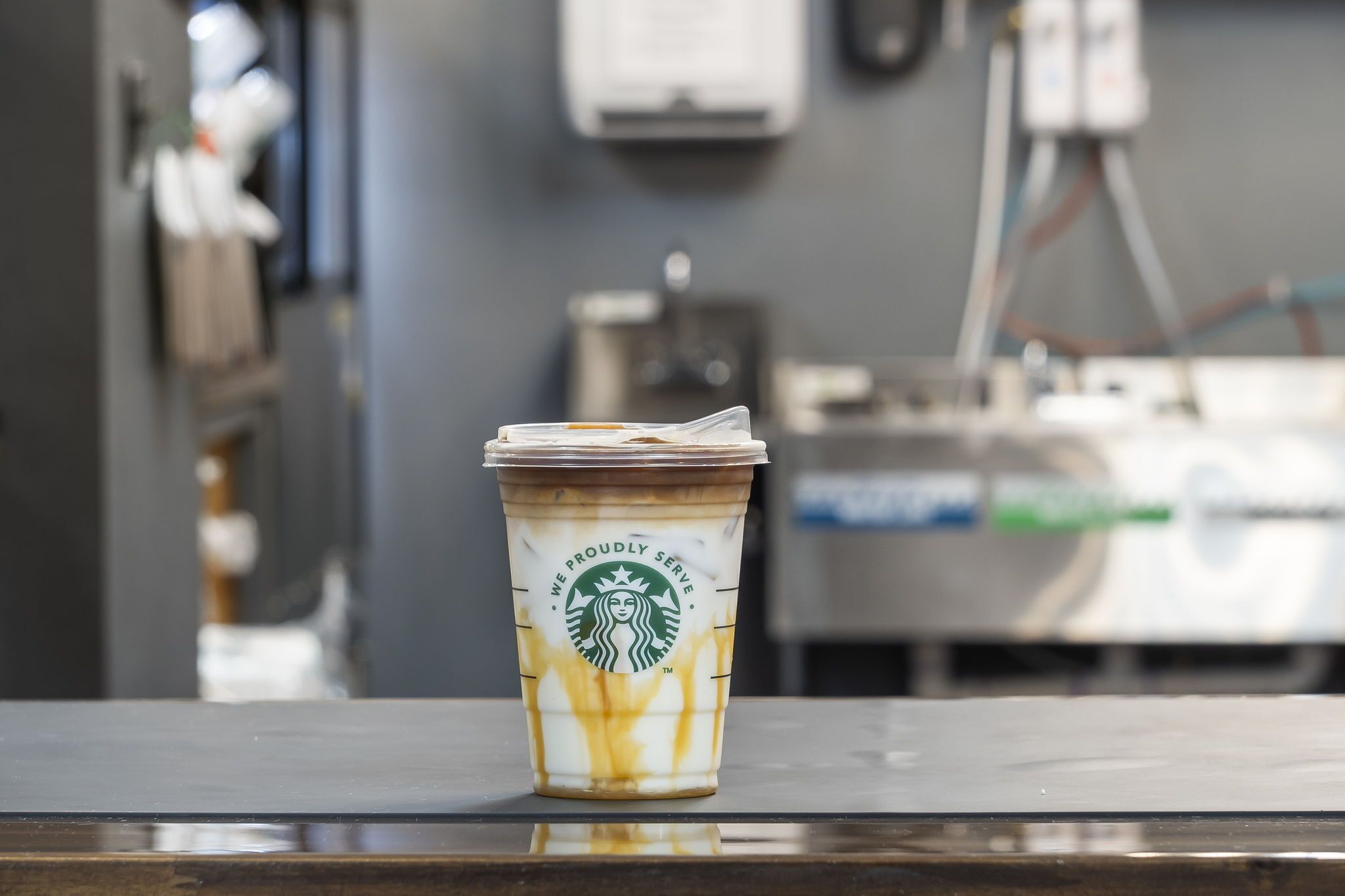 A Starbucks cup with a frothy drink on a table in a cafe.