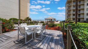 A wooden deck with white chairs and a table, a gazebo, and a view of the ocean. - Castle Reef 124 - Lovely location on No drive Beach (New Smyrna Beach)