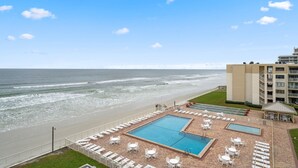 A pool area with lounge chairs and a view of the beach and ocean. - Castle Reef 124 - Lovely location on No drive Beach (New Smyrna Beach)
