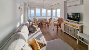A living room with a sofa, chairs, a TV, and a view of the sea. - Nice apartment in Algarrobo-Costa (Algarrobo-Costa)