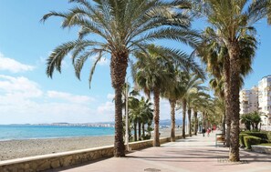 A coastal promenade lined with palm trees, a beach, and a cityscape in the background. - Nice apartment in Algarrobo-Costa (Algarrobo-Costa)