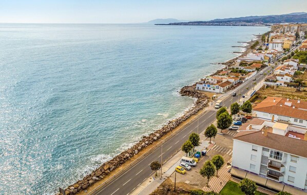 A coastal road with a stone seawall, lined with residential buildings and parked cars. - Nice apartment in Algarrobo-Costa (Algarrobo-Costa)