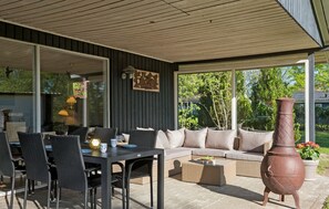 Relax in this serene outdoor space with a dining table, comfortable sofa, and lush views.