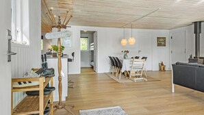 Un intérieur moderne avec un plafond en bois, un coin repas comprenant une table et des chaises, et un espace cuisine équipé d’une cuisinière.
