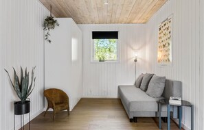 Relax in a serene space with a sofa, side table, and wicker chair.