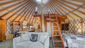 A yurt interior with a wooden ceiling, a sofa, a ladder, and a bed. - Unique 2Bds/1Bath Yurt | Kitchen, Wifi, Views! (Bozeman)