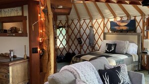 A cozy yurt interior with a bed, sofa, and wooden beams. - Unique 2Bds/1Bath Yurt | Kitchen, Wifi, Views! (Bozeman)