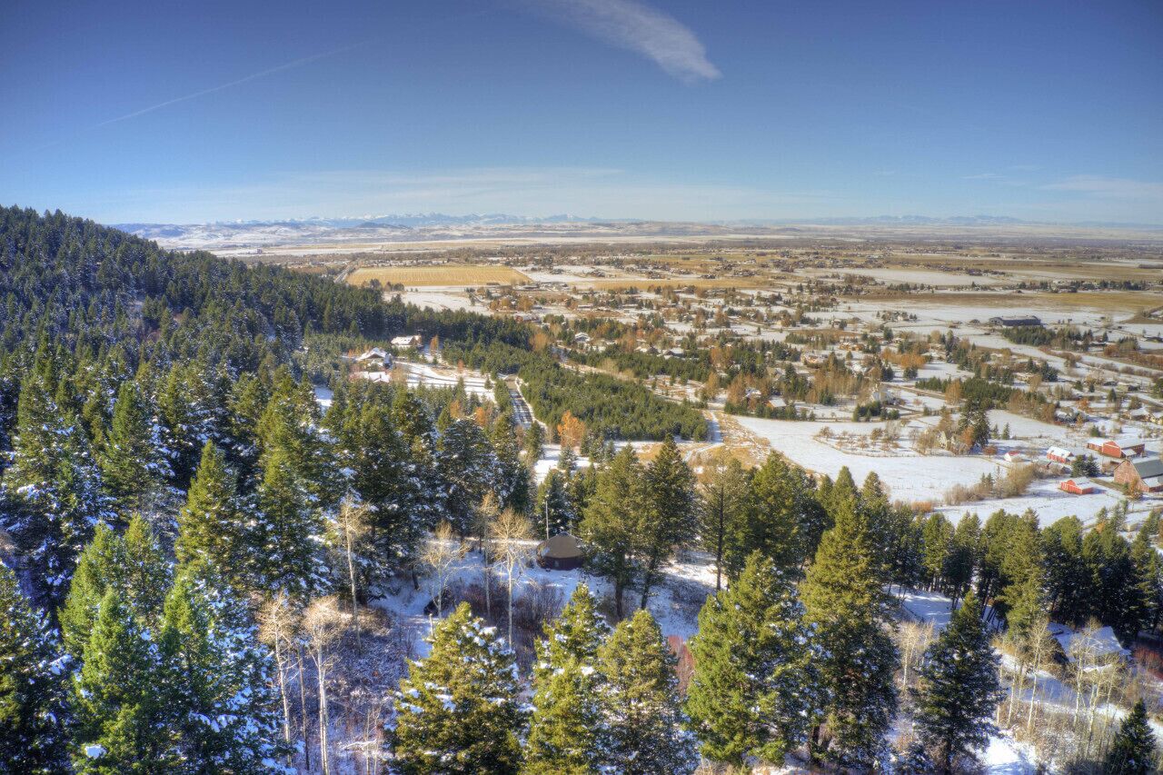A town with a mix of residential and commercial buildings, surrounded by dense forests and snow-covered fields.
