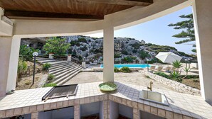 A pool area with a view of a rocky hillside, a staircase, and a sink with a bowl.