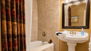 A bathroom with a bathtub, a sink, and a mirror.