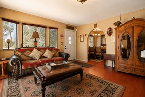 Una sala de estar con un sofá de cuero, una mesa de centro de madera y un espejo grande.