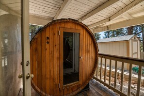 Eine hölzerne, fassförmige Tür mit Fensterglas, ein Holzboden und ein weißes Geländer.