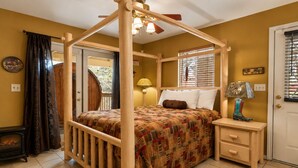 A four-poster bed with a quilt, a bedside lamp, and a small wooden nightstand.