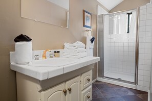 Ein Badezimmer mit Waschbecken, Spiegel, Handtuchhalter und Dusche.