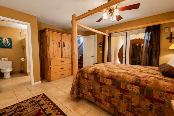 A bedroom with a wooden four-poster bed, a ceiling fan, and a quilted bedspread.