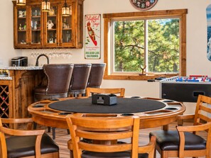 A cozy dining area with a round table, wooden chairs, and a foosball table.