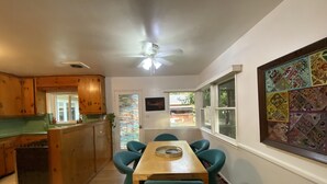 A kitchen with wooden cabinets, a dining table with chairs, a ceiling fan, and a window with a colorful view. - Vintage home near Rose Bowl & JPL/NASA. So many trails great for active folks    (Altadena)