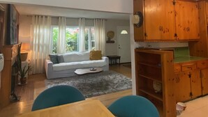 A living room with a sofa, a dining table with chairs, and wooden cabinets. - Vintage home near Rose Bowl & JPL/NASA. So many trails great for active folks    (Altadena)
