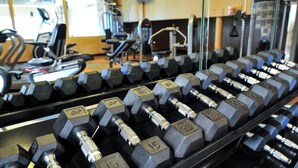 Een sportschool met rijen hexagonale gewichten, trainingsapparaten en een loopband.