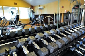 A gym with rows of hexagonal dumbbells, exercise machines, and a treadmill.