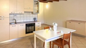 Eine moderne Küche mit hellen Holzschränken, einem eingebauten Backofen und einem weißen Esstisch mit Stühlen.