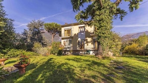 A two-story house with a balcony, surrounded by a well-maintained garden and trees. - Wonderful private villa for 12 guests with WIFI, TV, balcony and pets allowed, close to Viareggio (Camaiore)