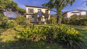 A two-story house with a balcony, surrounded by lush greenery and a well-maintained lawn. - Wonderful private villa for 12 guests with WIFI, TV, balcony and pets allowed, close to Viareggio (Camaiore)