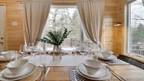 A wooden cabin with a dining table set for six, a vase with flowers, and a view of trees through the window. - Mins to Skiing! Hot Tub-Fire Pit-Hammock-BBQ-Games (Lake Harmony)